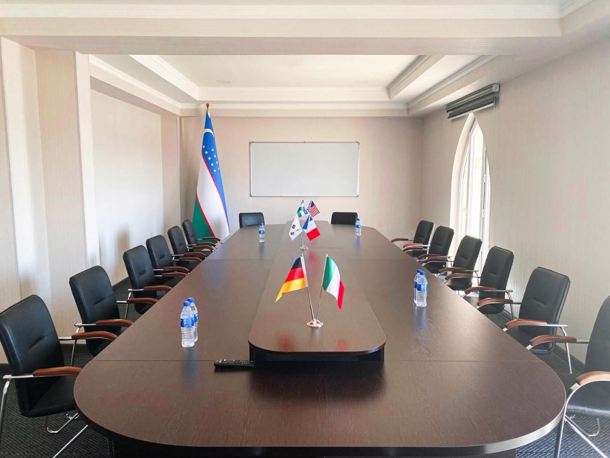 A conference room with a long table, flags, chairs, and a projector screen.