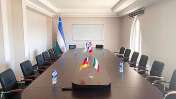 A conference room with a long table, flags, chairs, and a projector screen.