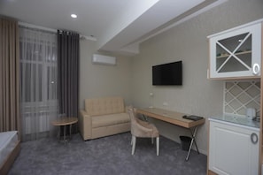 Hotellihuone, jossa on sänky, työpöytä, tuoli, televisio ja minibaari.