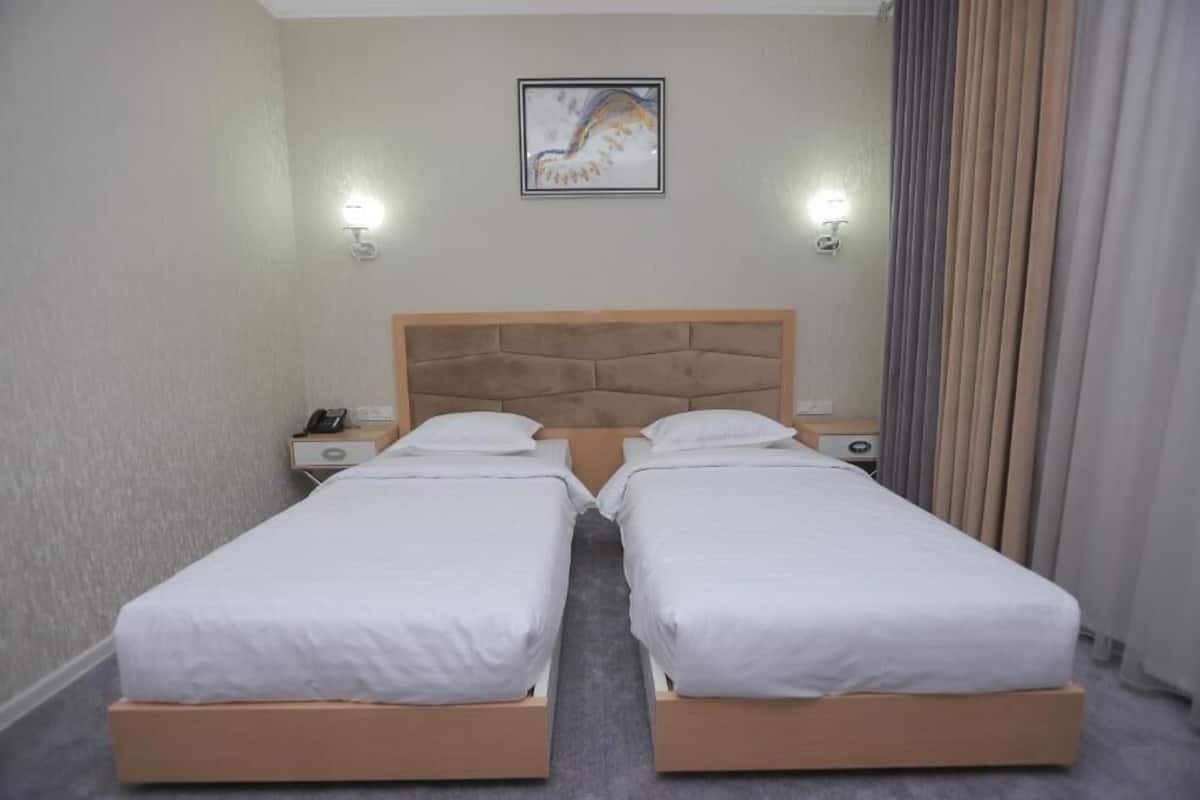 A double bed with a wooden headboard, two bedside tables with lamps, and a framed artwork on the wall.