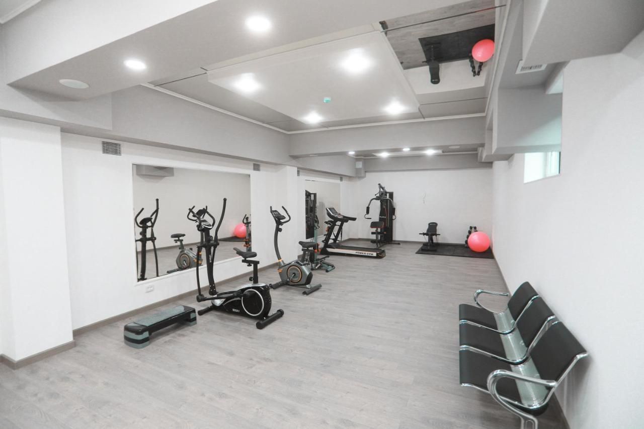 A gym with exercise equipment, a mirror, and a seating area.