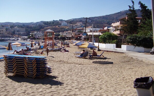 A beach with sun loungers, umbrellas, and a clear view of the sea.