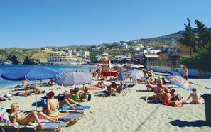 A beach with sun loungers, umbrellas, and people relaxing.