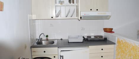 A compact kitchen with a sink, stove, and cabinets.