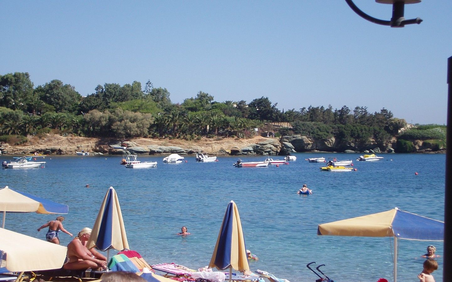 A beach with boats, umbrellas, and people.