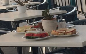 A dining table with plates of food, a potted plant, and a salt shaker.
