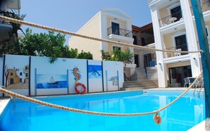 A swimming pool with a rope barrier, a lifebuoy, and a mural with sea-themed artwork.