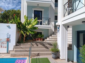 A multi-story building with a pool, outdoor seating, and potted plants.