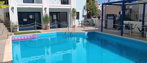 Una piscina con una barriera di corde, piante in vaso e zone relax all'aperto.
