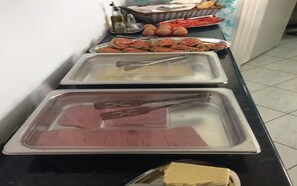 A buffet setup with various food items and utensils.