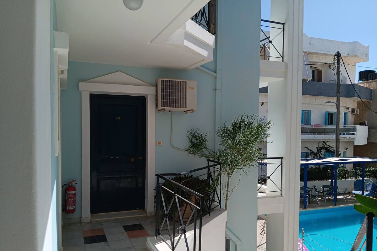 Un balcon avec une piscine, un extincteur et une porte portant le numéro 24.