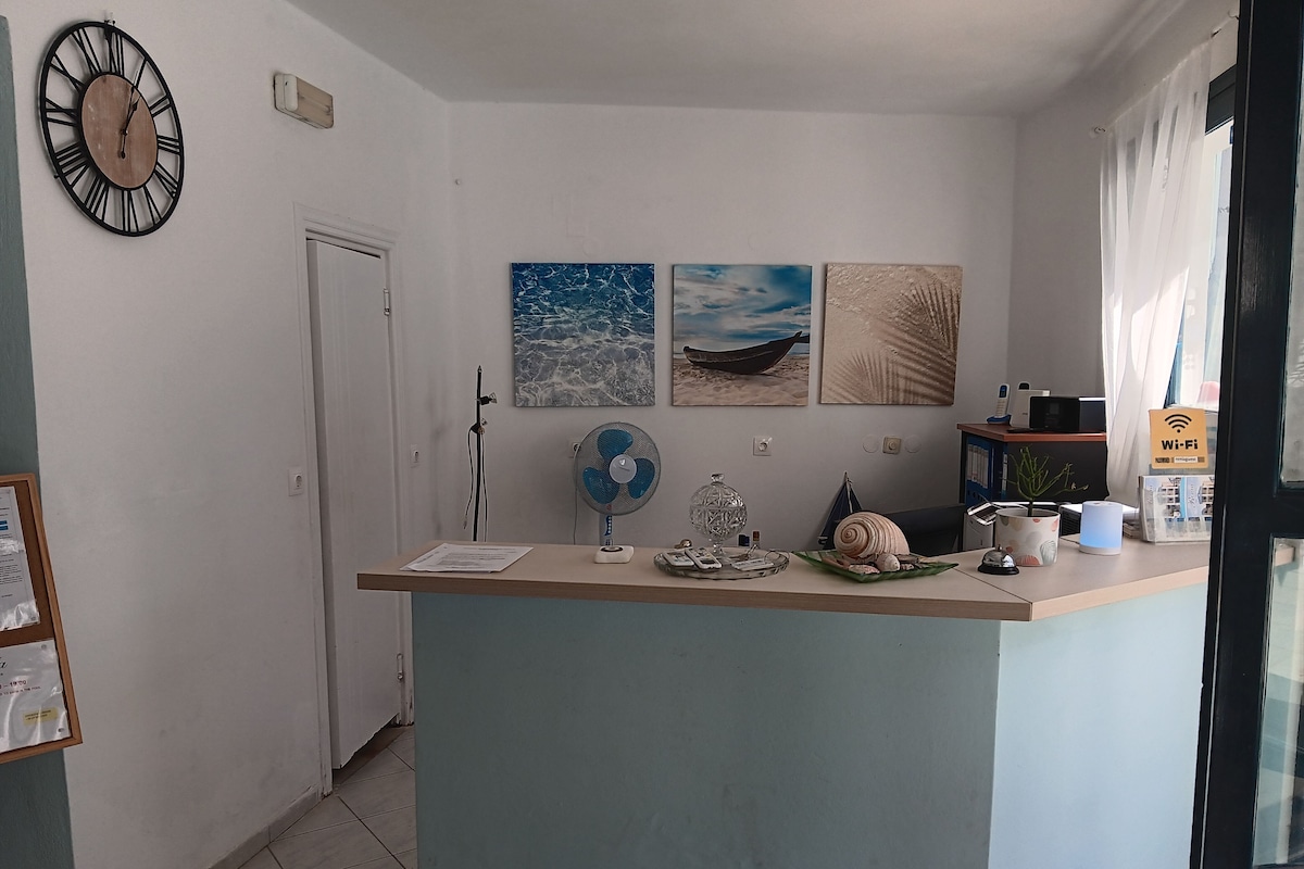 A kitchen with a clock, a fan, and artwork on the wall.