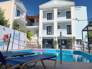 Un hotel con piscina, mobiliario exterior y un flotador.