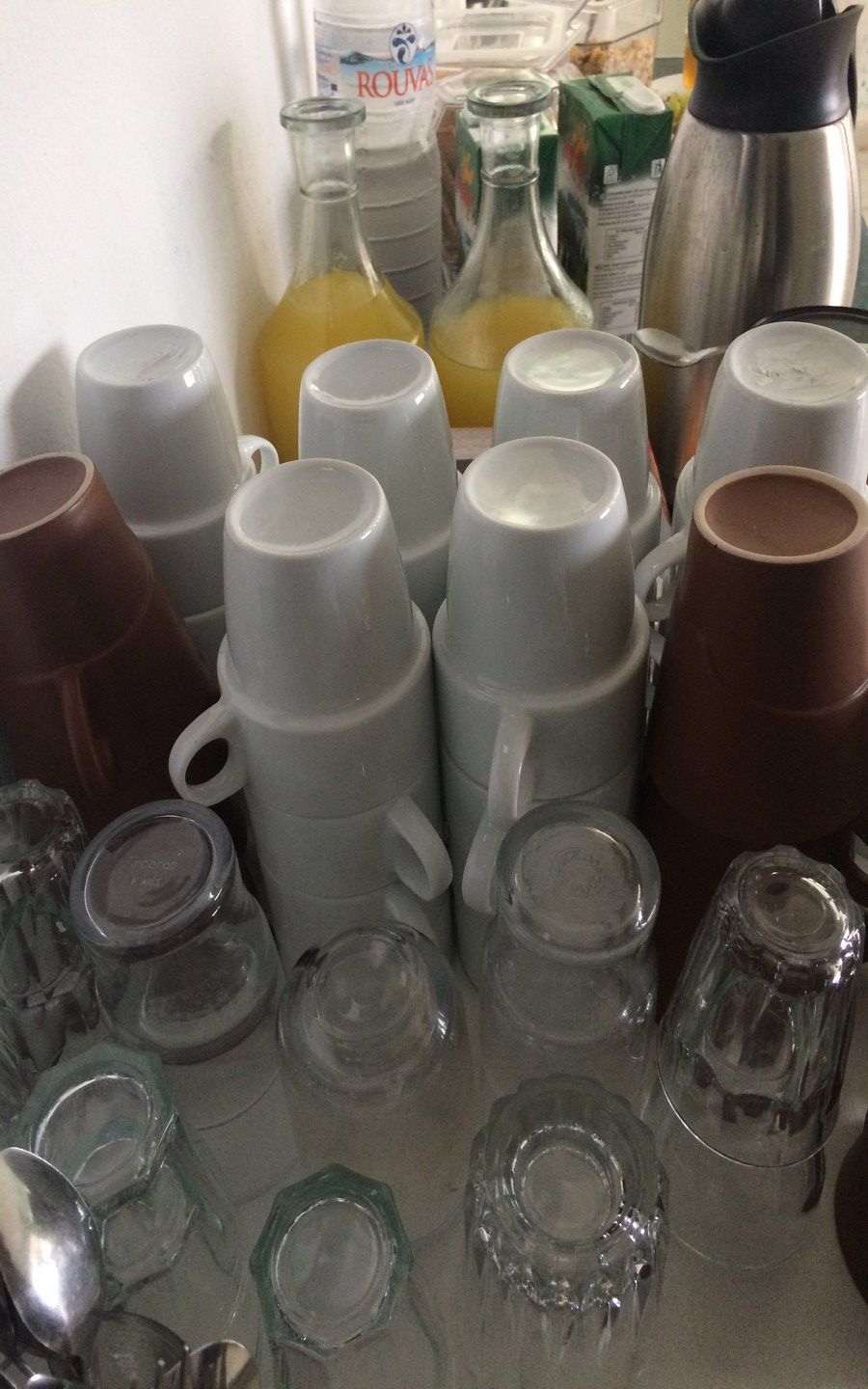 Un espace cuisine comprenant divers récipients en verre, notamment des bouteilles et des gobelets, ainsi qu’un distributeur d’eau.
