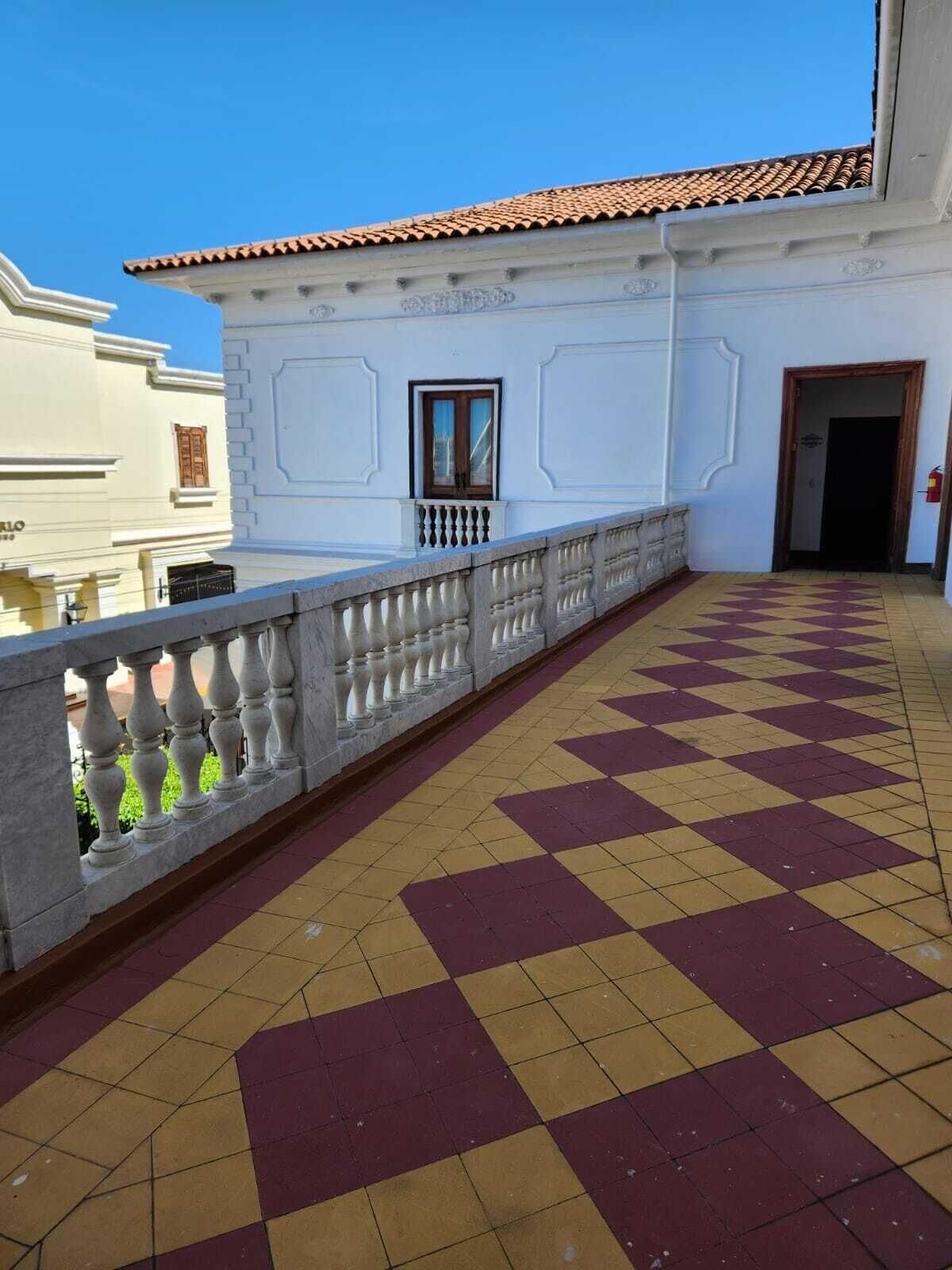 A balcony with a checkered floor, white walls, and a tiled roof.