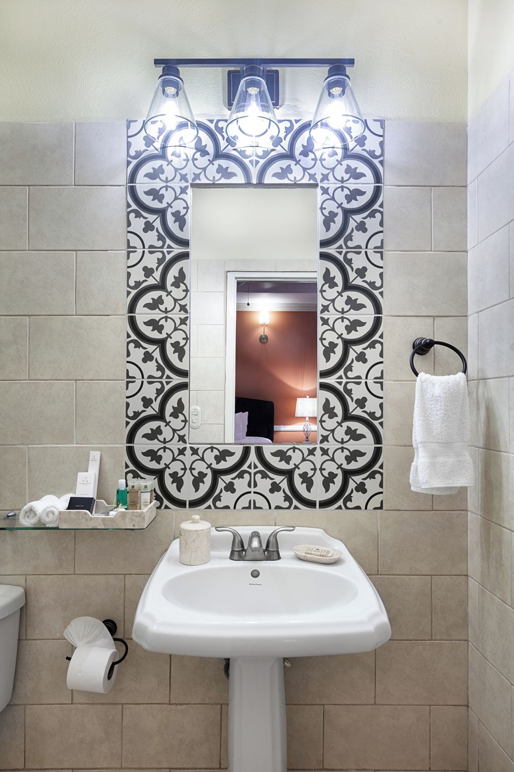 A bathroom with a white sink, a mirror, and patterned tiles.
