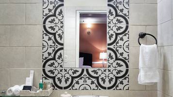 A bathroom with a white sink, a mirror, and patterned tiles.