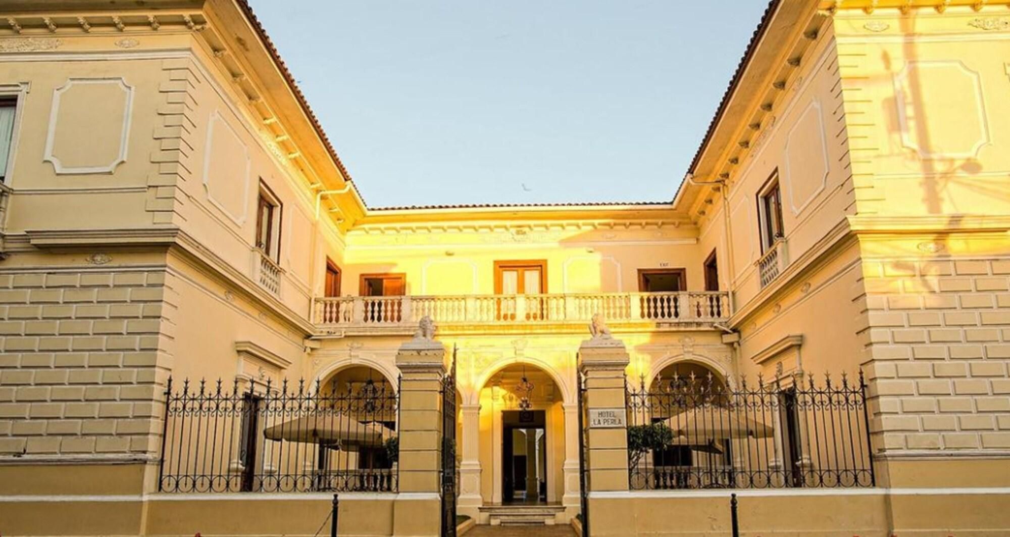 A building with a central entrance, two balconies, and a sign indicating 'HOTEL LA VERA.'