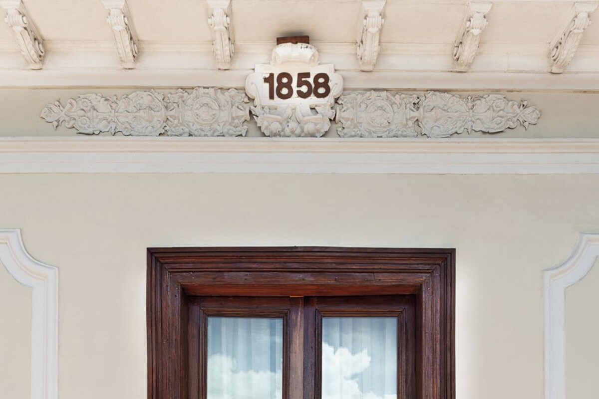 A wooden double door with a glass panel, a number plaque above it, and a yellow and red patterned floor.