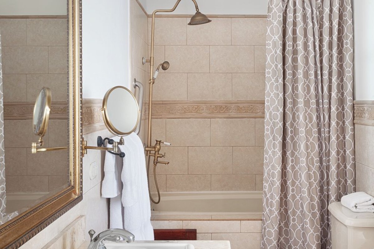 Un baño con bañera, inodoro, lavabo y un espejo grande.