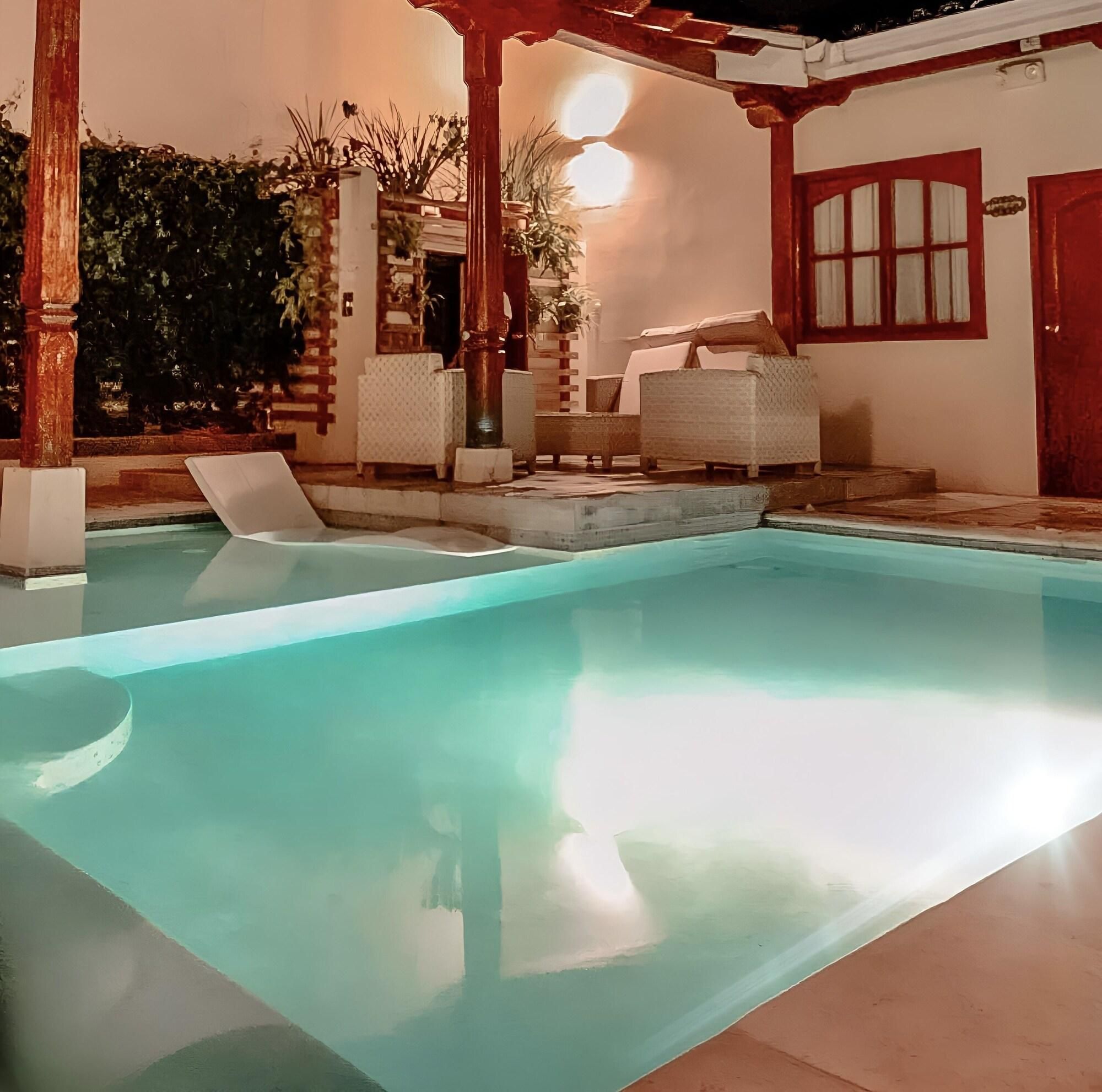 Une piscine avec des chaises longues, une pergola et une porte dotée d’une fenêtre.
