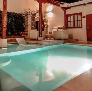 A swimming pool with lounge chairs, a pergola, and a door with a window. - Hotel La Perla León (León)