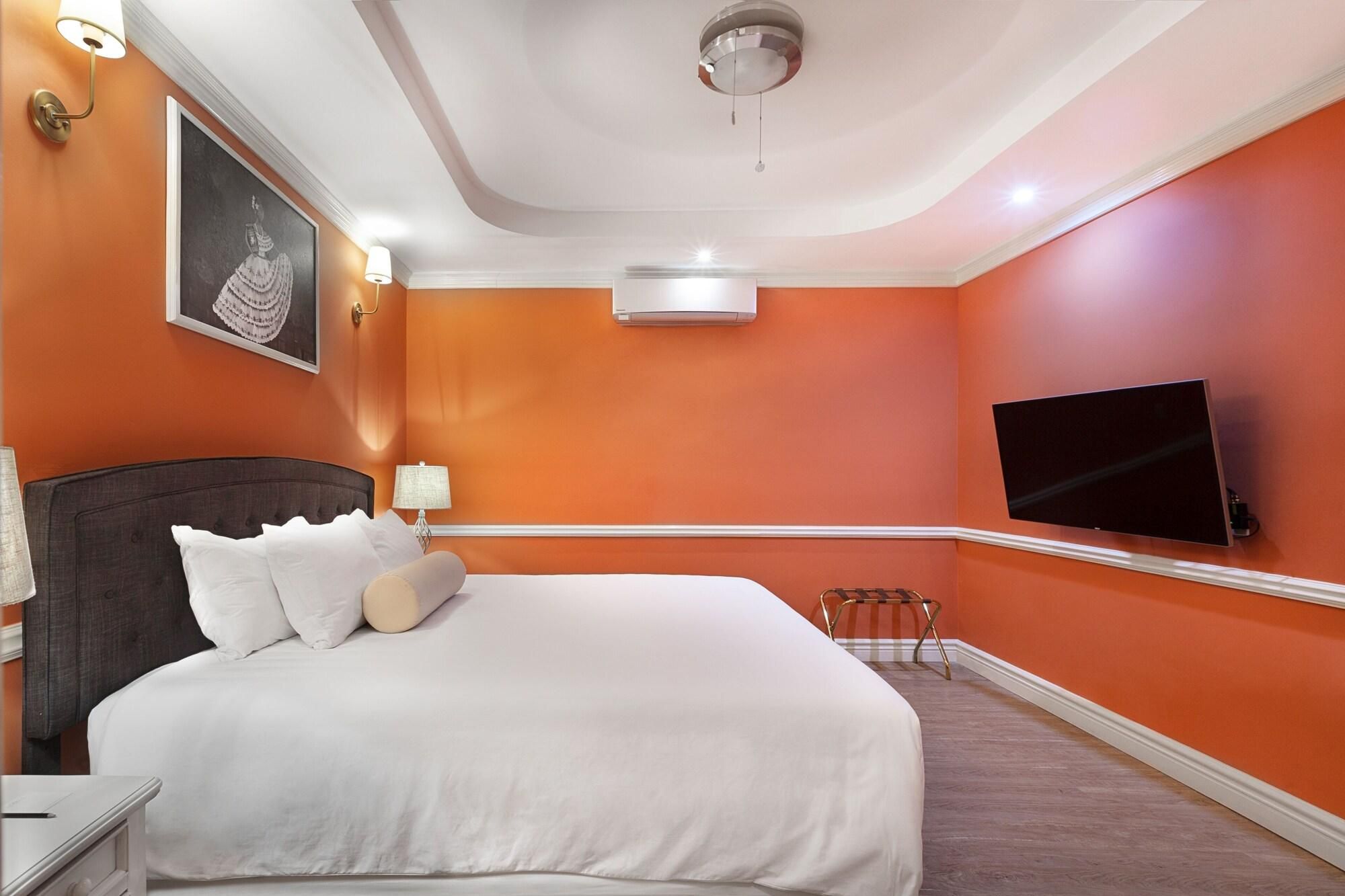 A hotel room with a large bed, a flat-screen TV, an air conditioning unit, and a framed picture on the wall.