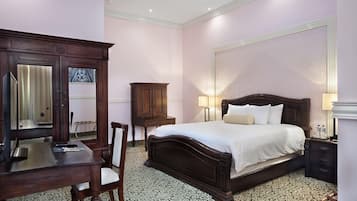 A bedroom with a bed, a desk, a chair, a cabinet, and a mirror.