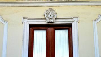 Een gevel met een raam, voorzien van een witte balustrade en een decoratieve kroonlijst.