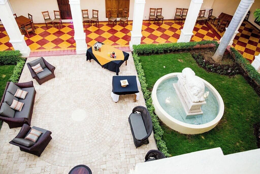 A courtyard with checkered flooring, outdoor furniture, a fountain, and a statue.