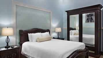 A bedroom with a large bed, two bedside tables, a nightstand, a mirror, and a wall with a decorative panel.