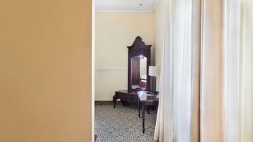 Un pasillo con alfombra estampada, un espejo y una mesa.