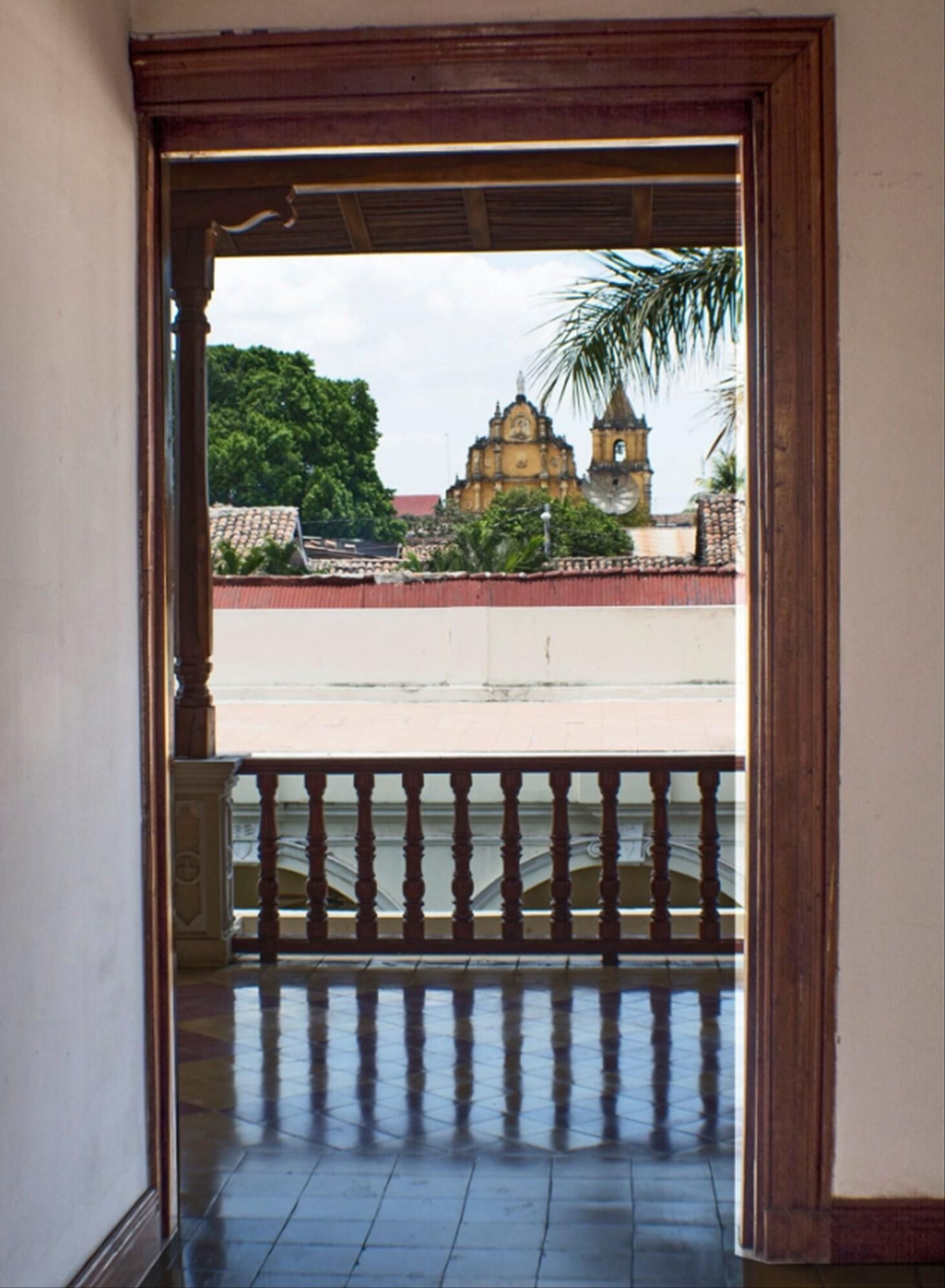 Un'apertura che dà su un balcone con vista su un edificio storico con una torre dell'orologio.