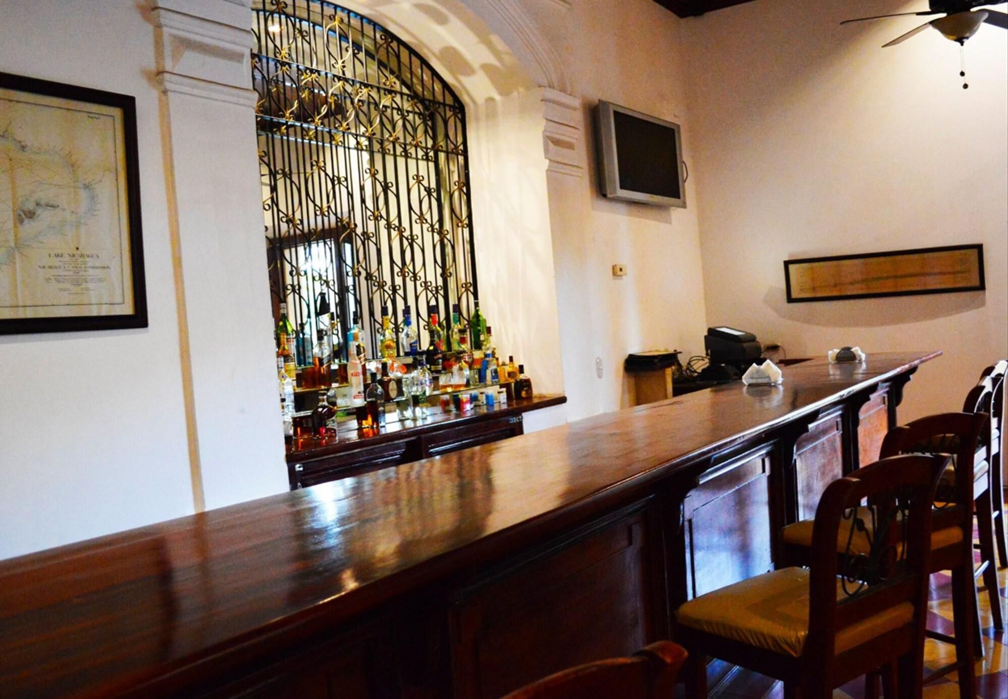 A bar area with a wooden counter, bar stools, a television mounted on the wall, and a decorative metal gate.