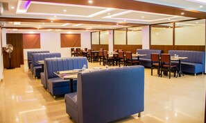 Ein modernes Restaurant mit blauen Sitzbänken und Tischen, einem polierten Boden und einer Decke mit Einbaustrahlern.