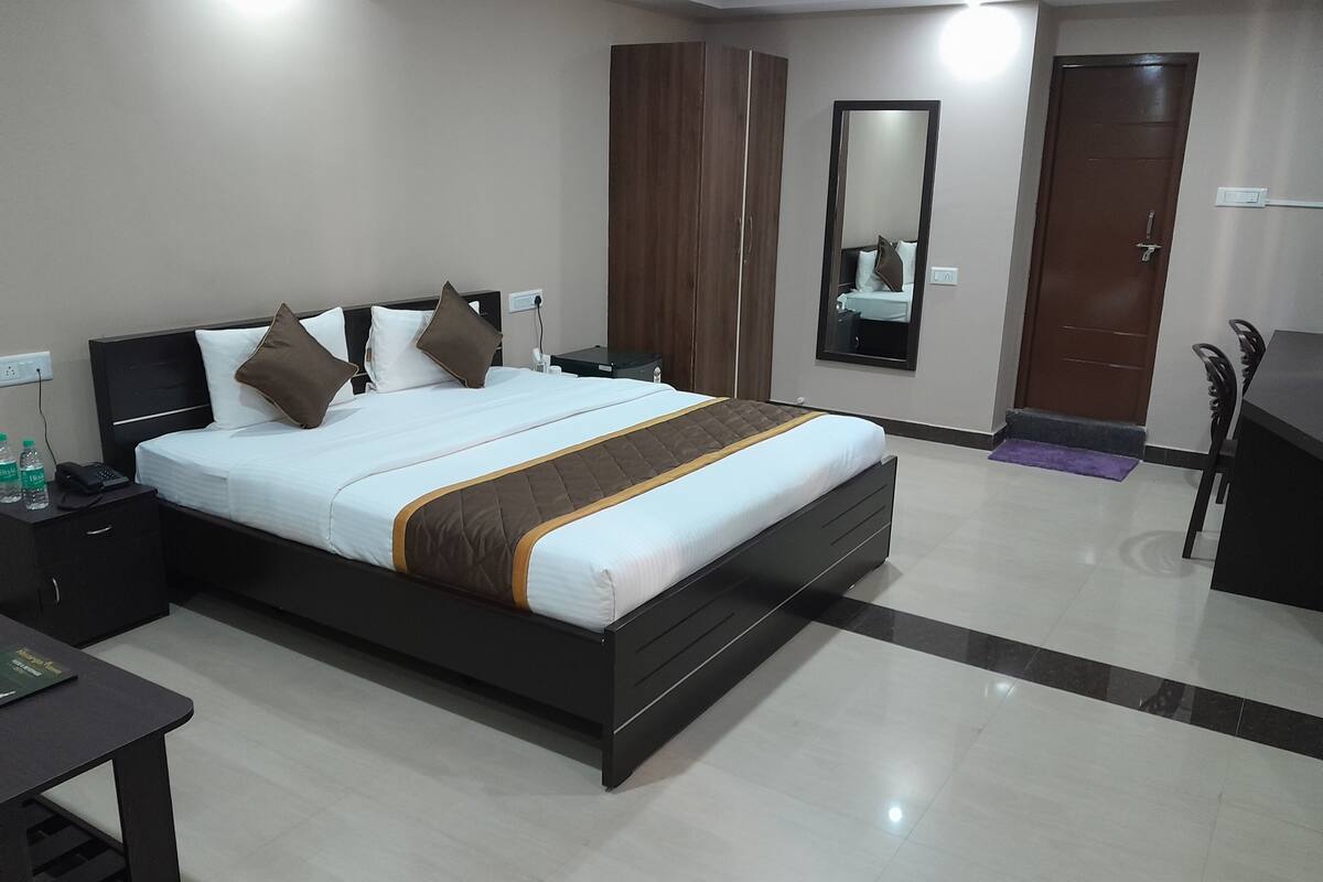 Ein modernes Hotelzimmer mit einem großen Bett, Nachttischen, einem Schreibtisch und einem Spiegel.