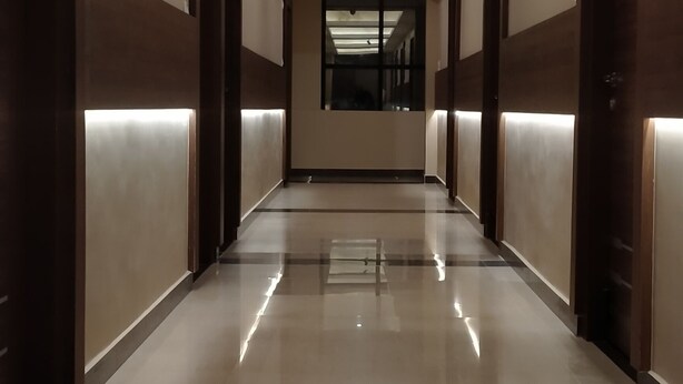 A long, well-lit hallway with a reflective floor and doors on both sides. - The Nisarga Grand Bangalore India (Bengaluru)