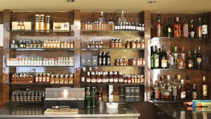 A bar area with shelves stocked with various liquor bottles and a counter with bar tools. - The Nisarga Grand Bangalore India (Bengaluru)
