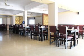 Un restaurante con techos altos, candelabros y un piso de baldosas limpias.