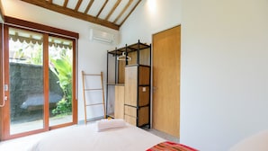 Une chambre à coucher comprenant un lit, une armoire, une étagère et une porte-fenêtre coulissante donnant sur un espace extérieur.