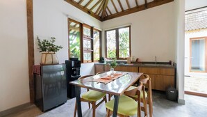 Une cuisine compacte comprenant une table à manger, des chaises, un réfrigérateur et une machine à café.