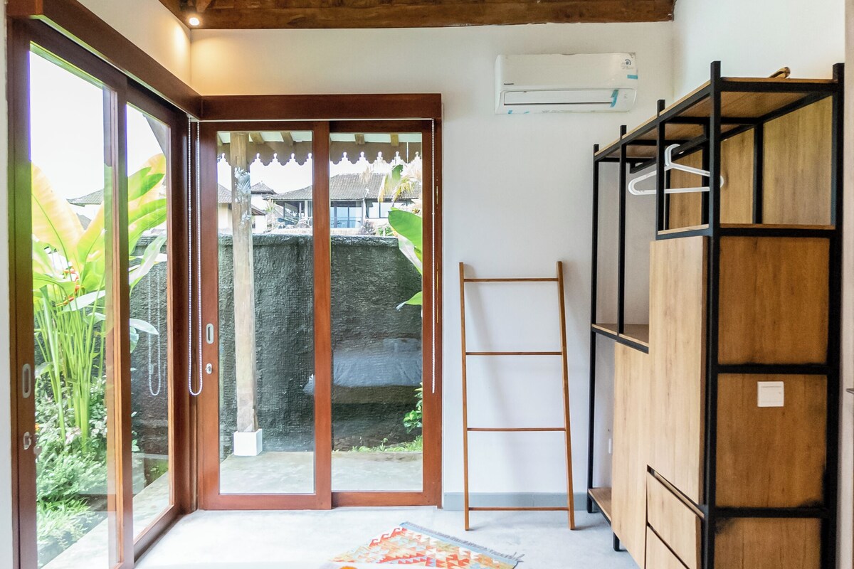 Ein Schlafzimmer mit einem Bett, einem Holzschrank, einer Leiter und einer Glastür zum Außenbereich.