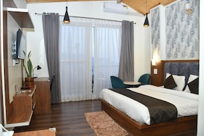 A bedroom with a bed, a desk, a chair, and a window with curtains. - Hotel Le Halcyon Kasau (Solan)