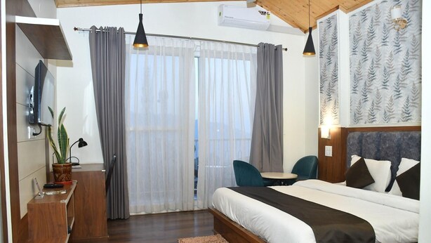 A bedroom with a bed, a desk, a chair, and a window with curtains. - Hotel Le Halcyon Kasau (Solan)