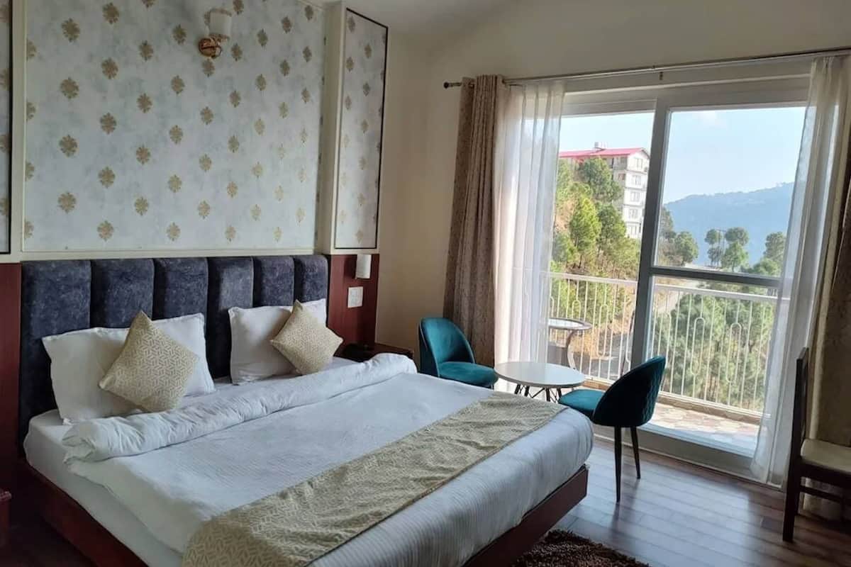 A hotel room with a large bed, a balcony with a table and chairs, and a view of the outdoors.