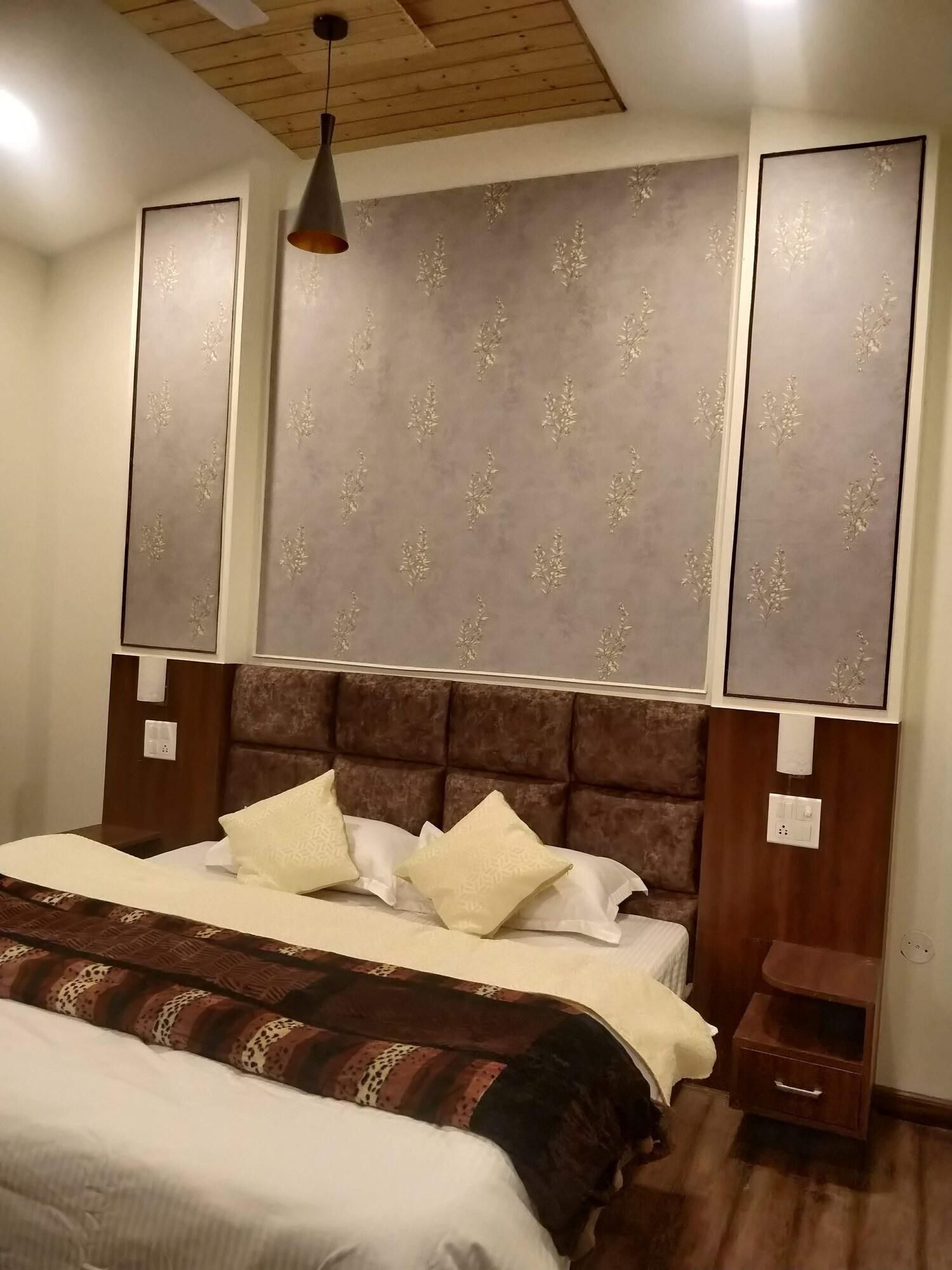 A bedroom with a large bed, a headboard with a decorative panel, a nightstand, and a hanging light fixture.