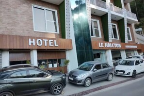 A hotel building with a 'HOTEL' sign and a 'LE HALCTON' sign. There are cars parked in front. - Hotel Le Halcyon Kasau (Solan)