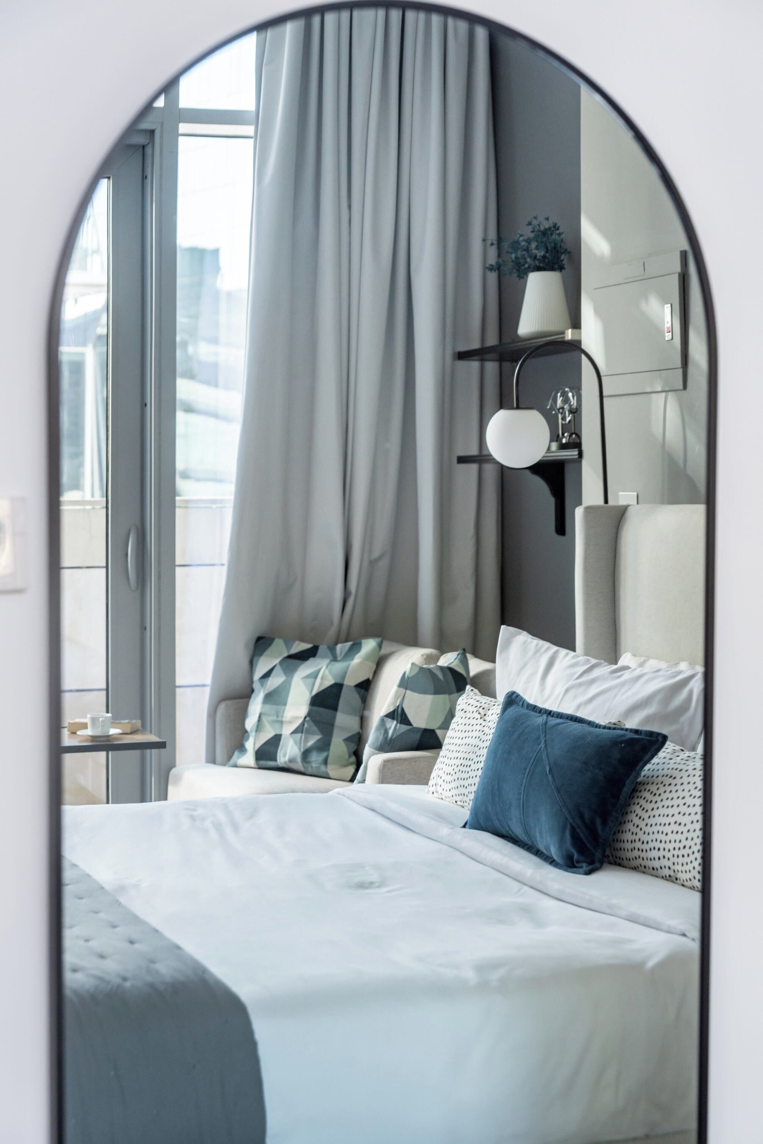 Ein ordentlich eingerichtetes Schlafzimmer mit Bett, Kissen, Nachttisch und Lampe.