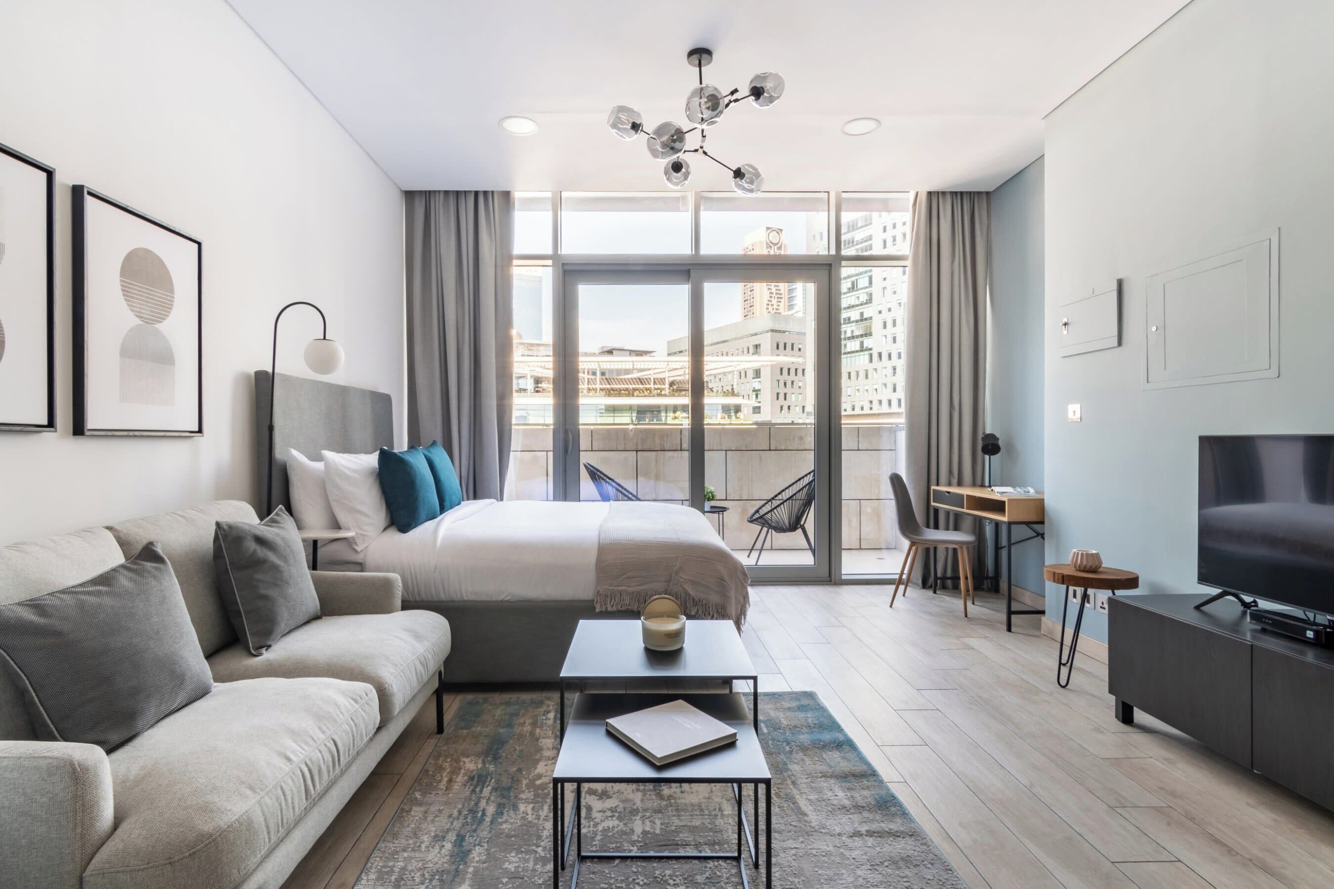 Ein modernes Hotelzimmer mit einem großen Bett, einer Sitzecke, einem Schreibtisch und einem Fernseher.