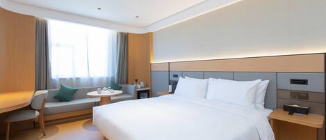 Una habitación de hotel moderna con una cama grande, un sofá, una mesita y una mesita de noche.